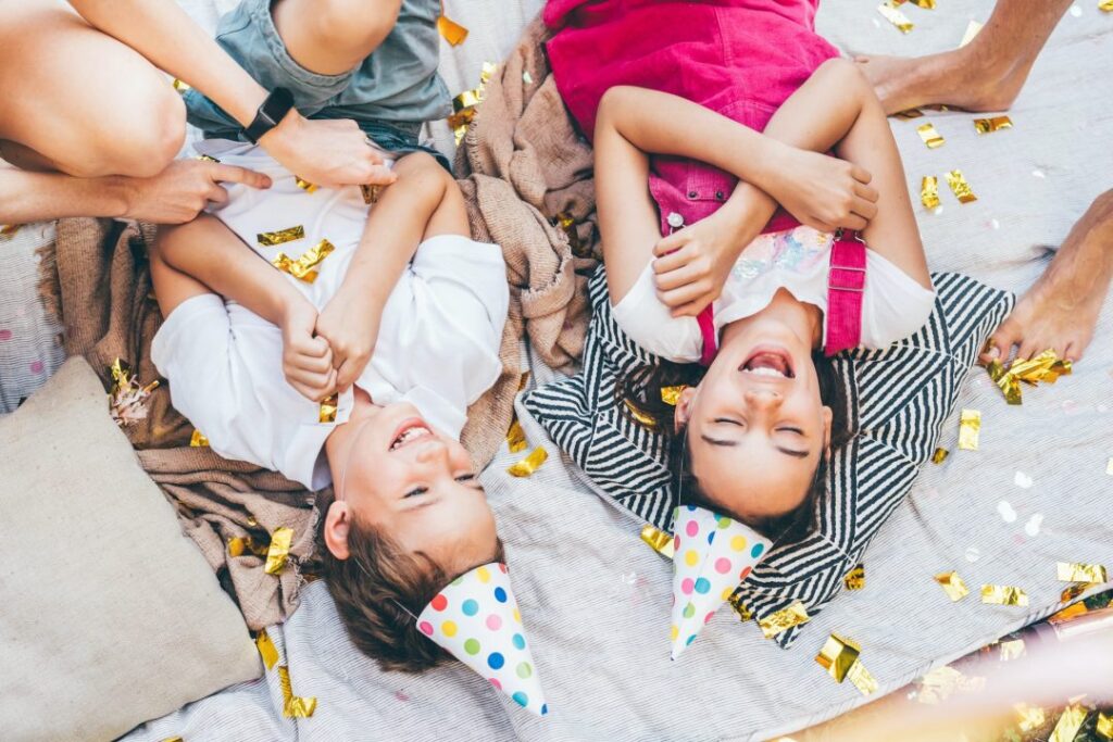 children laughing on plaid with confetti and air balloons at birthday celebration